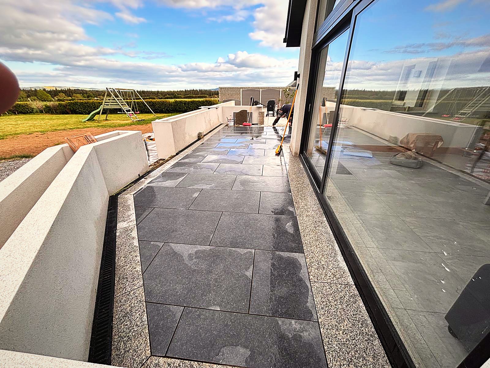 Dark porcelain terrace with linear drain beside glass doors